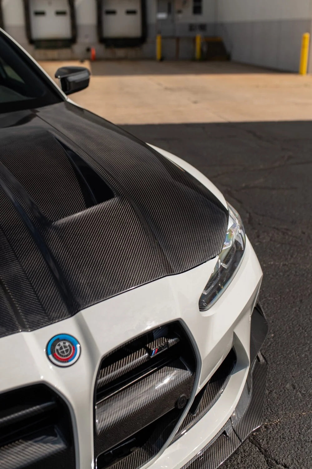 Carbon fiber front bumper and hood on a white performance car